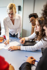 Teenage Students: Working with Teacher. A group of students concentrating on a class project with their teacher. From a series of related images.