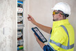 © puhimec - Electrical technician looking focused while working in a switchboard with fuses.