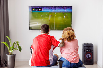 couple watching football on tv and cheering for their team