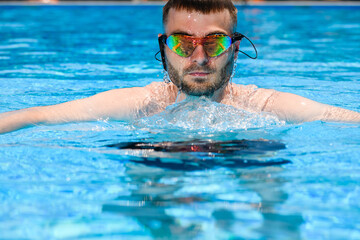 Professional male swimmer in goggles in pool