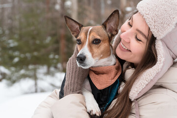 happy woman hugging dog walking in winter park