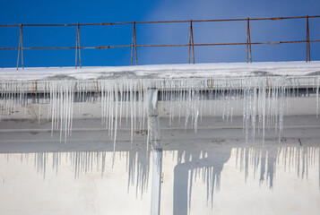 Wall Mural - Icicles hang from the roof of the house.