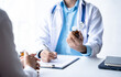 © PaeGAG - Doctor and patient sitting and talking at medical examination at hospital office, close-up. Therapist filling up medication history records. Medicine and healthcare concept.