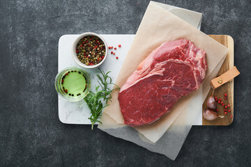 Steaks. Fresh New York Steaks raw with spices rosemary and pepper on black marble board on gray background. Top view. Mock up.