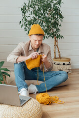 Middle aged man knitting at home. Knitting project in progress. Man learning a new hobby