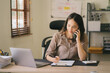 © Kritdanai - Portrait of a beautiful Asian woman looking at laptop screen while sitting at working desk in the office