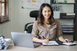 © Kritdanai - Portrait of a beautiful Asian woman looking at laptop screen while sitting at working desk in the office