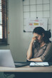 © Kritdanai - Portrait of a beautiful Asian woman looking at laptop screen while sitting at working desk in the office