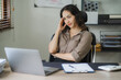 © Kritdanai - Portrait of a beautiful Asian woman looking at laptop screen while sitting at working desk in the office