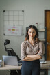 © Kritdanai - Portrait of a beautiful Asian woman looking at laptop screen while sitting at working desk in the office
