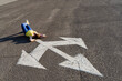 © VISTA by Westend61 - Woman lying down with hands behind head near three way direction arrow sign on road