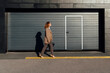 © VISTA by Westend61 - Young businesswoman walking on street by corrugated wall