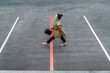 © VISTA by Westend61 - Businesswoman walking over red line at parking lot