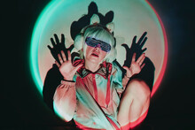 Woman With Bunny Ear Muff And Neon Glasses Gesturing Against Black Background