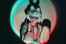 Woman Wearing Neon Glasses And Ear Muff Against Black Background
