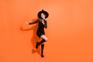 Poster - Full size photo of nice young woman dance look empty space dressed trendy black halloween witch garment isolated on orange color background