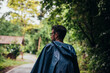 © NoemiEscribano - Man wearing a raincoat walking in the middle of a road next to the forest