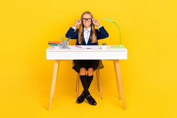 Canvas Print - Full size photo of positive girl with straight hairdo dressed blue jacket sit at desk touch glasses isolated on yellow color background