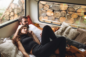 Wall Mural - Young beautiful loving couple travelling across country in the van. Millennial man and woman in a travel camper. Cozy atmosphere, vacations vibe