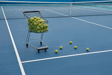 Horizontal No People Shot Of Cart Full Of Tennis Balls And Net Prepared For Training In Blue Colored Court, Professional Sport Concept, Copy Space