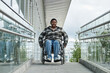 © Seventyfour - Front view portrait of smiling black woman in wheelchair moving down ramp in city, urban accessibility, cop space