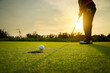 © sattahipbeach - golfer putting a golf ball into a last hole on the green, golf course on summer sunset evening time with copy space