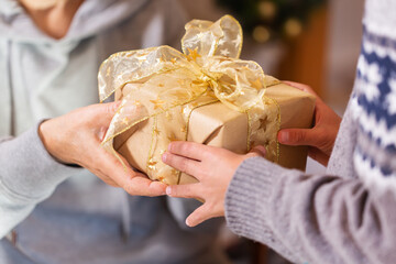 Hands of senior woman and a child holding Christmas gift