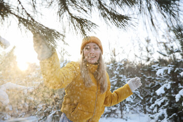 Wall Mural - Woman shaking off snow from tree branch in forest on winter day