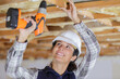 © auremar - woman with building puncher drilling hole in ceiling