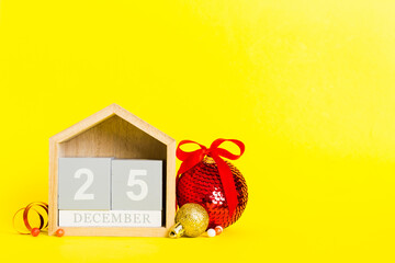 25 december. Christmas composition on colored background with a wooden calendar, with a gift box, toys, bauble copy space