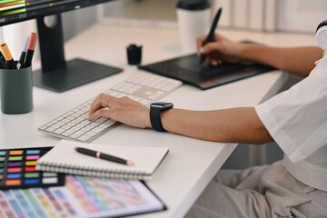 Cropped view of young creative woman using graphic tablet, working for design project at home office