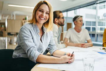 Wall Mural - Cheerful young designer sitting in a meeting with her colleagues