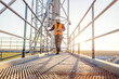 © dusanpetkovic1 - A heavy industry supervisor is walking on the high metal construction with tablet in his hands and monitoring works.