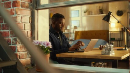 Poster - Young Black Man Using Laptop at Home. Doing Inspirational Remote Work During the Day. Specialist Working on Computer, Writing a Creative Project Plan. Shot from Outside the Window.