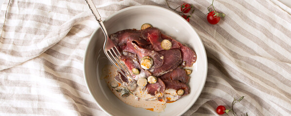 Wall Mural - a bowl of veal appetizer with vitello tonnato sauce on a light marble table