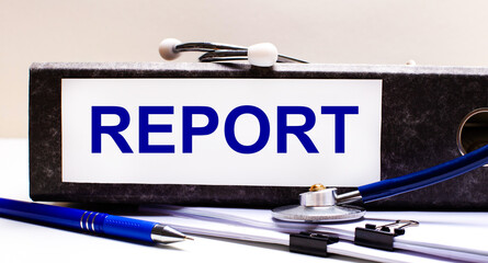 Fototapete - The desktop has a stethoscope, a blue pen, and a gray file folder with the text REPORT. Medical concept