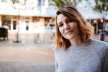 Young woman standing downtown looking seriously into camera