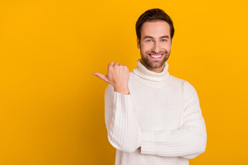 Wall Mural - Photo of cheerful handsome guy indicate thumb empty space wear white sweater isolated yellow color background