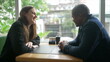 © Marco - Young diverse couple sitting at coffee shop table talking. Couple speaking at cafe place restaurant. Two people dating