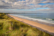 Beadnell Bay from the southern end, on the Northumberland coast, a designated Area of Outstanding Natural Beauty AONB, known for its wide beaches high sand dunes punctuated by dark whinstone outcrops