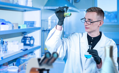 Poster - biologist man. young employee of biological laboratory. guy with colorful liquids in flasks. man in 
