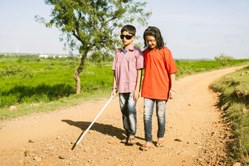 Teenager girl helping to blind brother by walking each other at mountain - concept of caregiver,friendship bonding and disability.