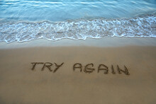 Try Again Written In The Sand On The Beach With The Sea Washing Up The Shore