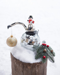 Wall Mural - model of a toy metal excavator and a miniature snowman stand on a mirror ball. merry christmas concept