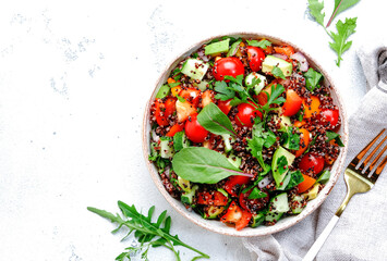 Quinoa tabbouleh salad with tomatoes, paprika, avocado, cucumbers and parsley. Traditional Middle Eastern and Arabic dish. White kitchen table background, top view