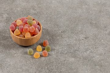 Wall Mural - Close up photo of fresh sweet marmalade in wooden bowl over grey background