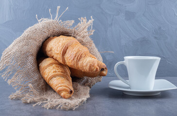 Two fresh French croissant with Coffee on grey background