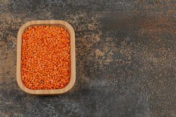 Raw red lentils on wooden plate