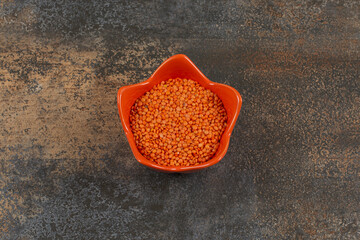 Uncooked red lentils in orange bowl