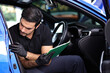 © Thongtawat - Portrait of an Auto Service Technician holds a pre-delivery inspection checklist for physical and interior inspection that the car repair shop.